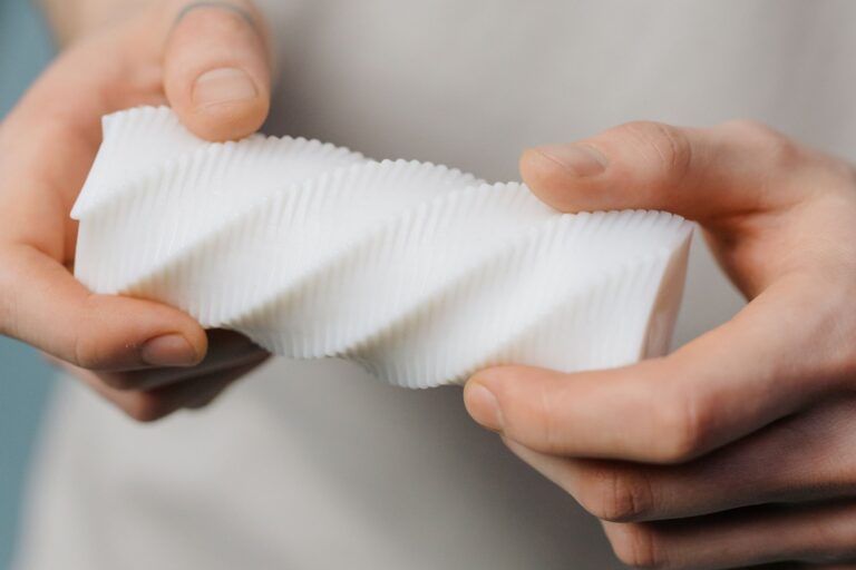 Close-up of layer height stairs and layer lines on a white twisted 3D print held in two hands