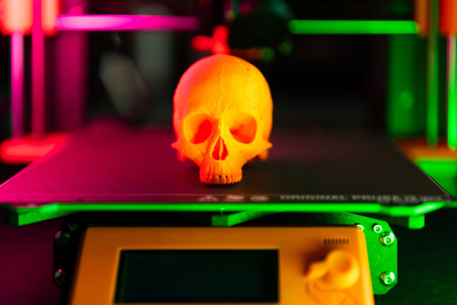 Orange 3D printed skull on a printer bed with fine, barely visible layer lines